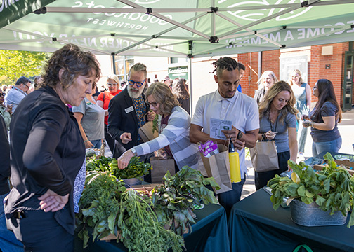 People pick vegetables from a farm stand table