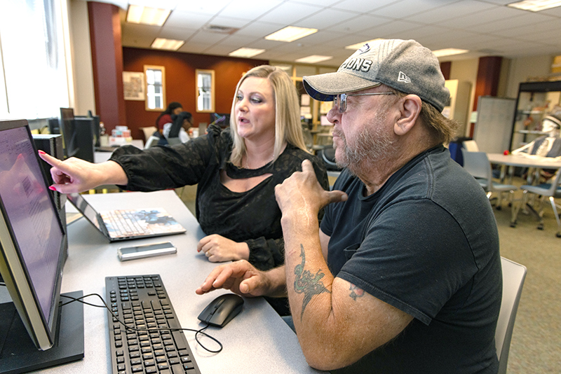two students at a computer, one student pointing at the screen