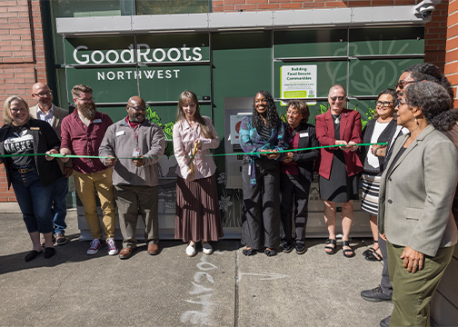 Large group stands in front of green lockers cutting ribbon for opening event