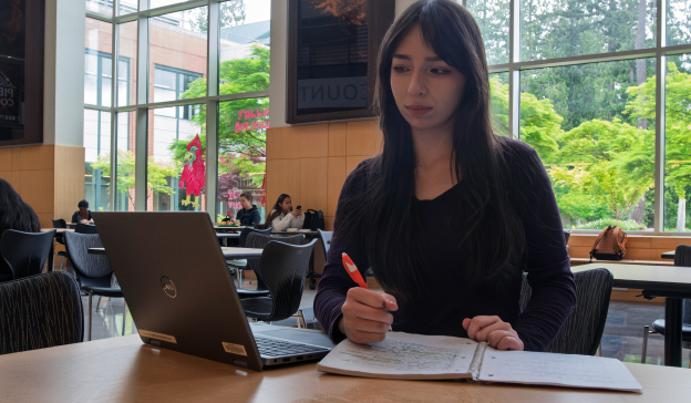 Student with laptop and notebook studying at table