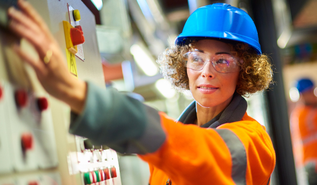 engineer in hard hat and protective clothing adjusting control panel