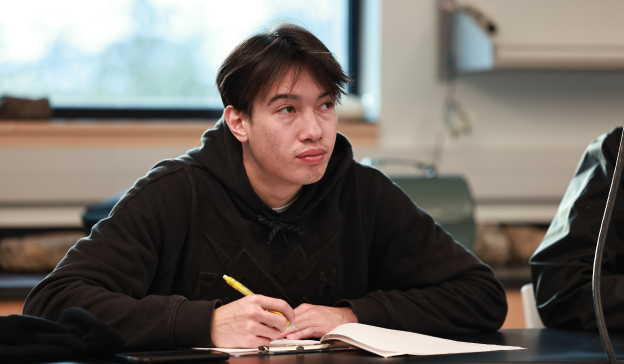 College student attending a history class, taking notes during a lecture on historical events.